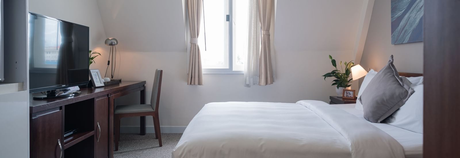 A bedroom with a bed, a desk, and a television | Studio | Central Mansions, Phnom Penh