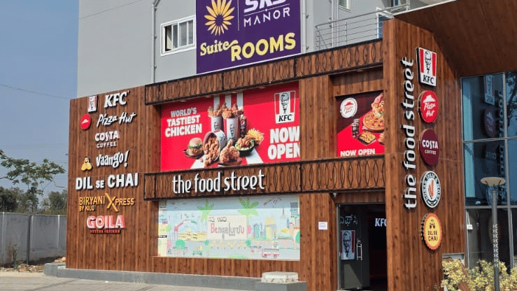 Commercial building entrance with storefronts, signage and a paved pedestrian area.