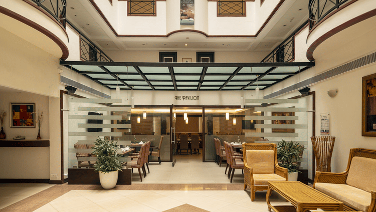 Pavilion at The Residency Karur features a patterned floor, seating areas, and glass-enclosed spaces under a skylight.