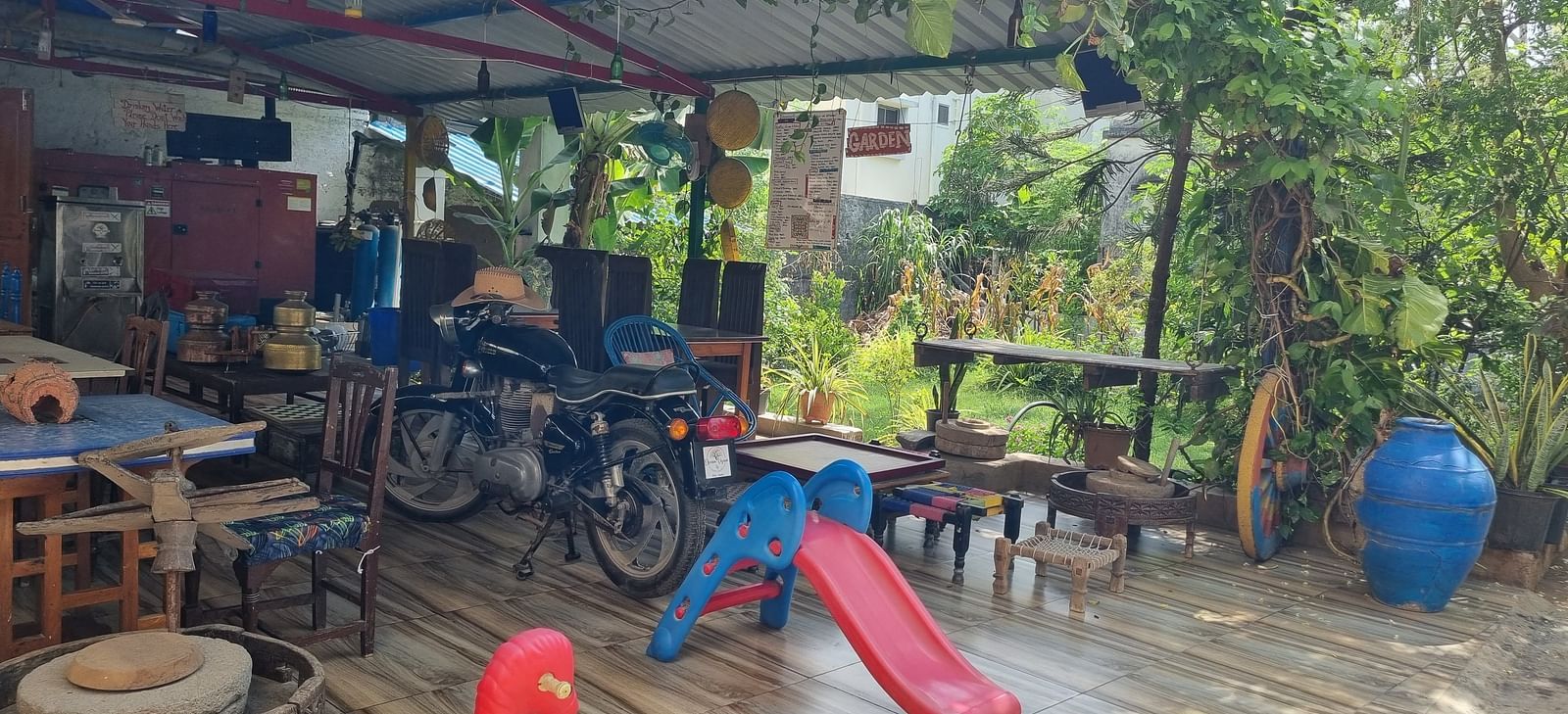 The kids' play area with surrounded by lush greenery along with a motor cycle kept under the shed at Dream Vision Guest House.