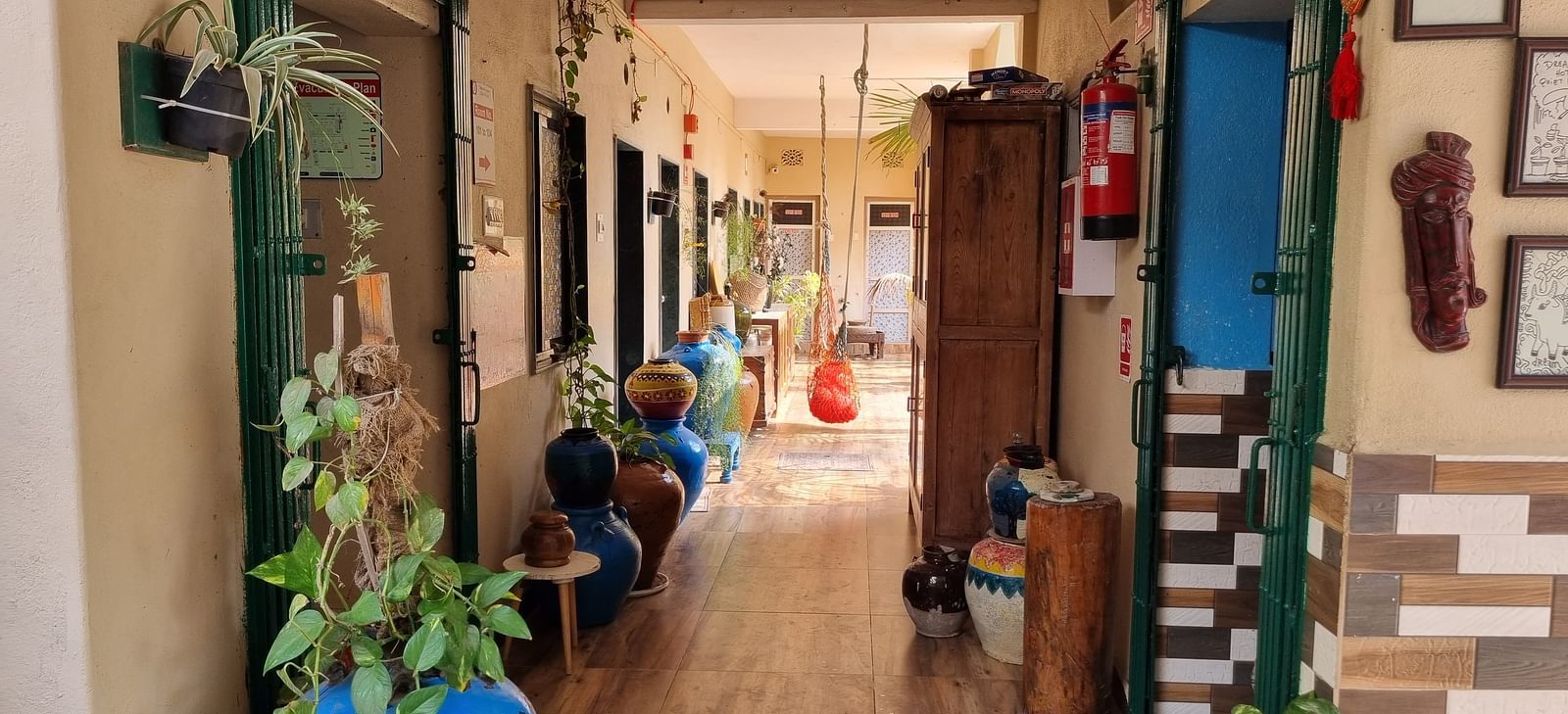 The corridor at the Dream Vision Guest House in Diu surrounded with plants and doors opening to the rooms.