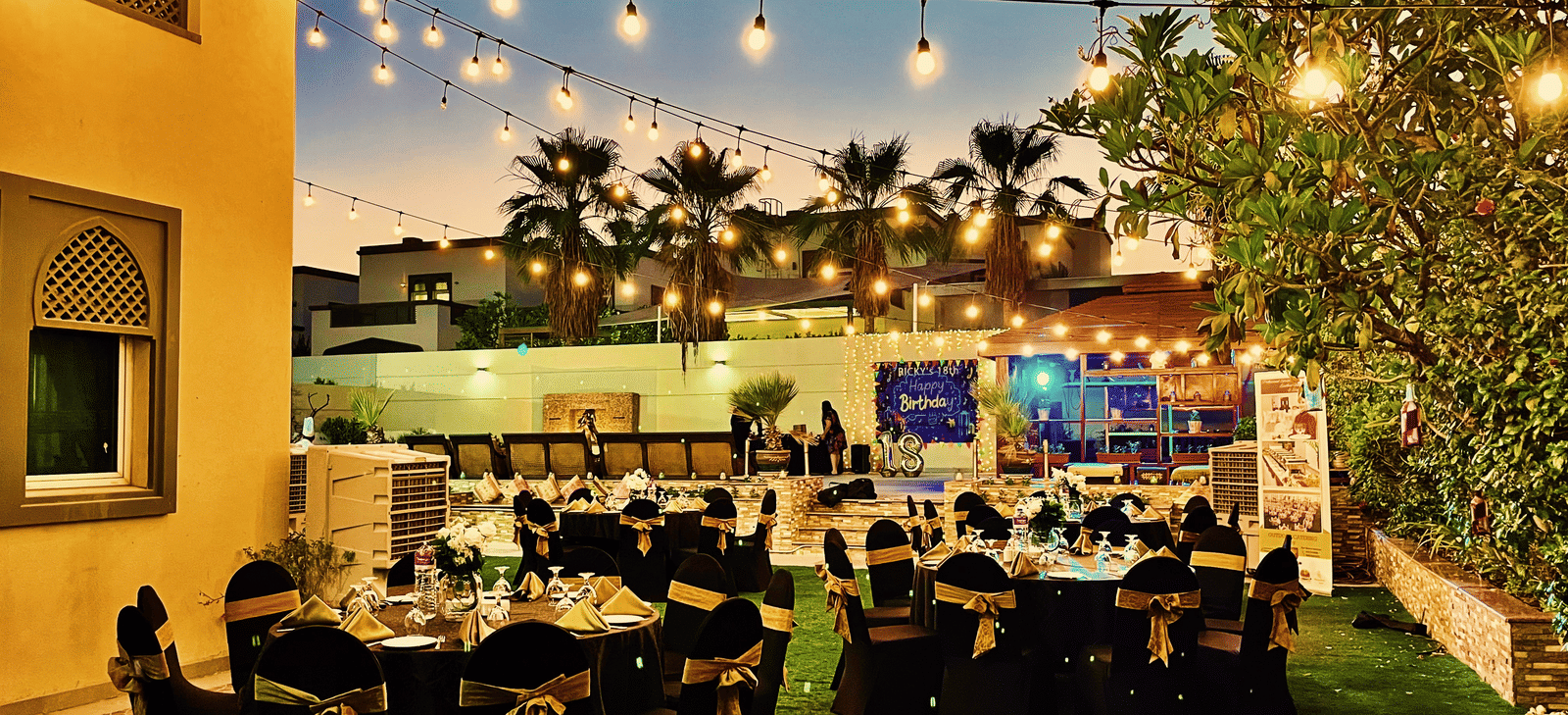 Outdoor dining setup with tables and chairs near greenery at Marco Polo Hotel.