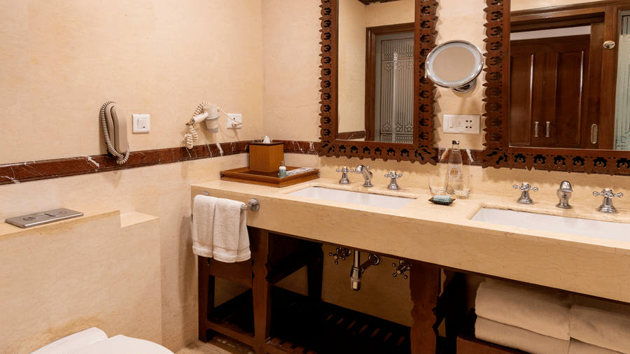 image of the bathroom with two separate mirrors of the Club Room at The Claridges Nabha Residence