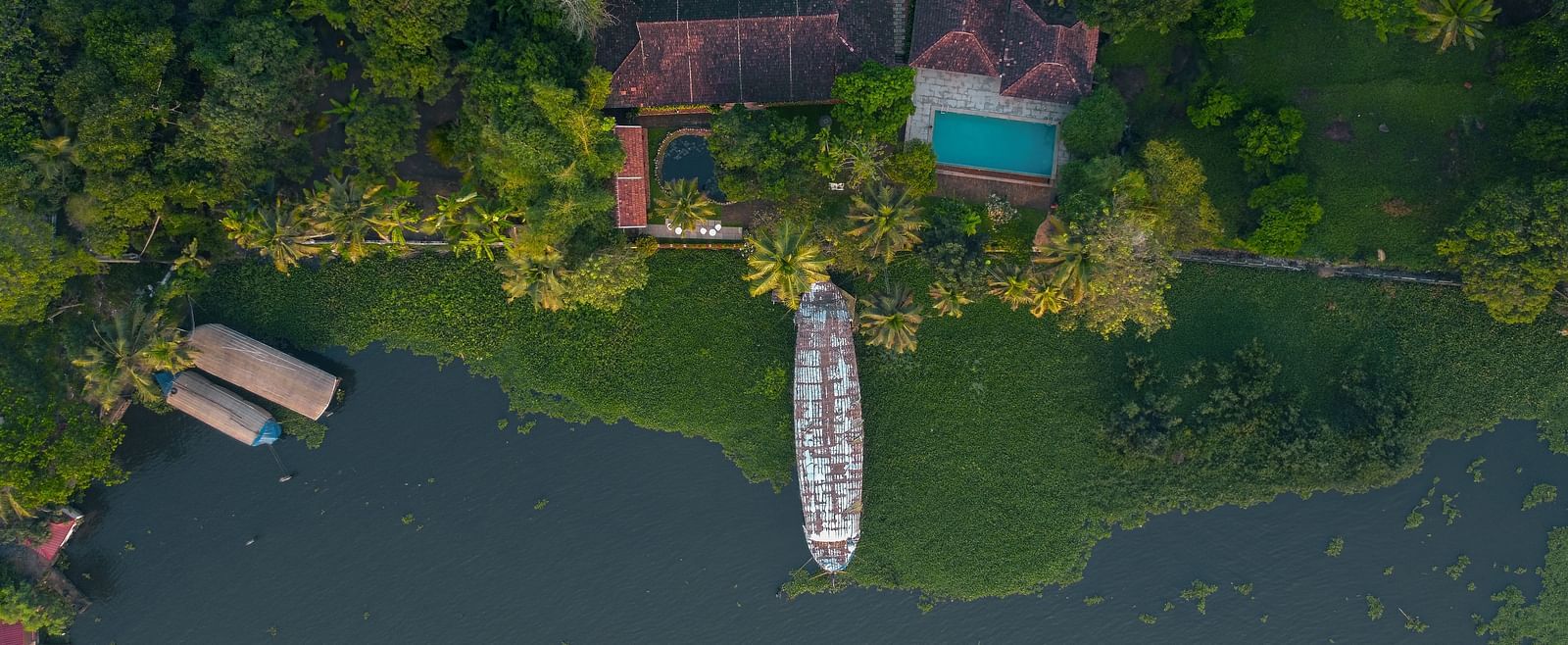 An aerial shot of BluSalzz Villas - Muhamma Resort, Alleppey surrounded by greenery and the Vembanad Lake
