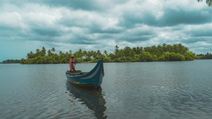 A view of a rowboat from a distance that is in a waterbody with an island in the distance as seen during a Trip to Gavi.