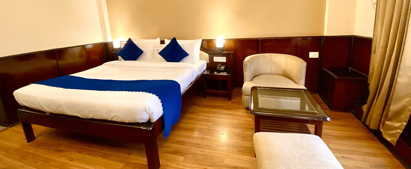 A bedroom with warm lights illuminating each side of the bed at DLS Park Grace, Haridwar.