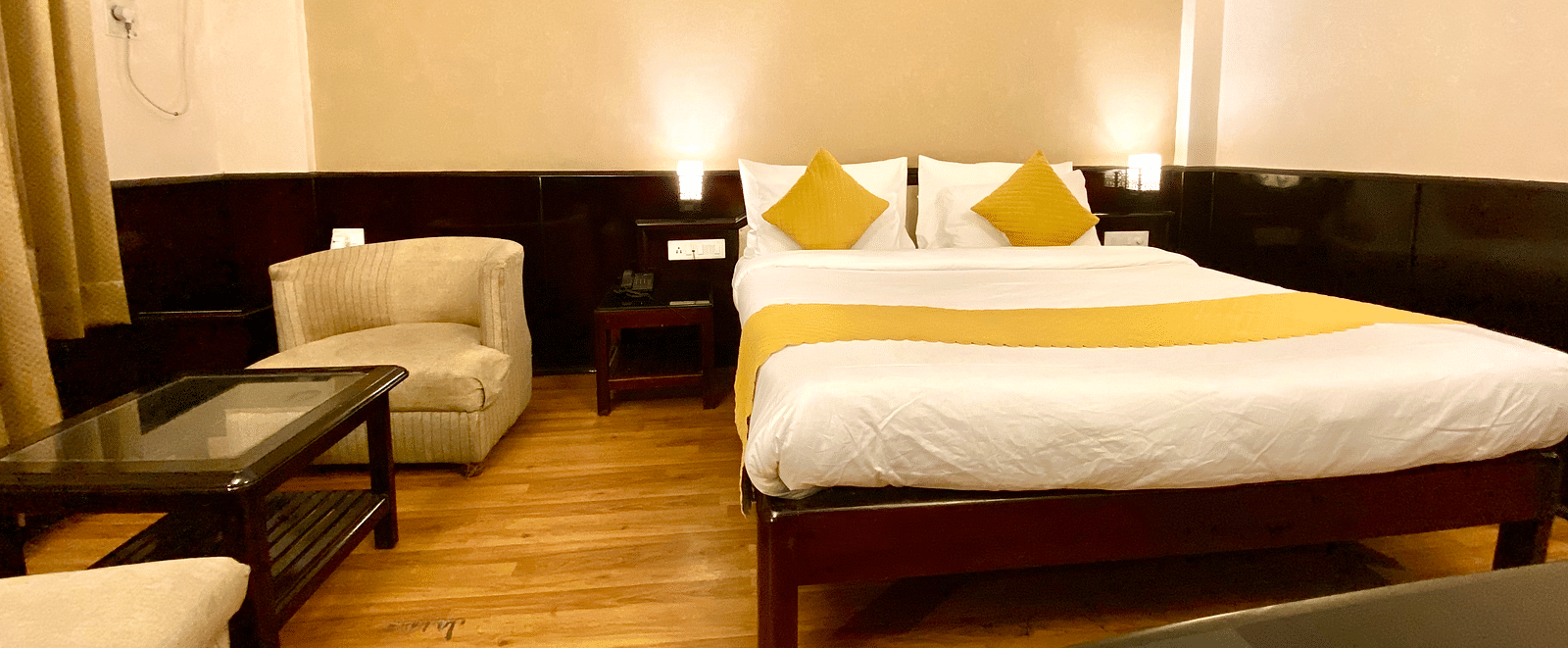 A bedroom with a cushioned chair and a coffee table beside it at DLS Park Grace, Haridwar.