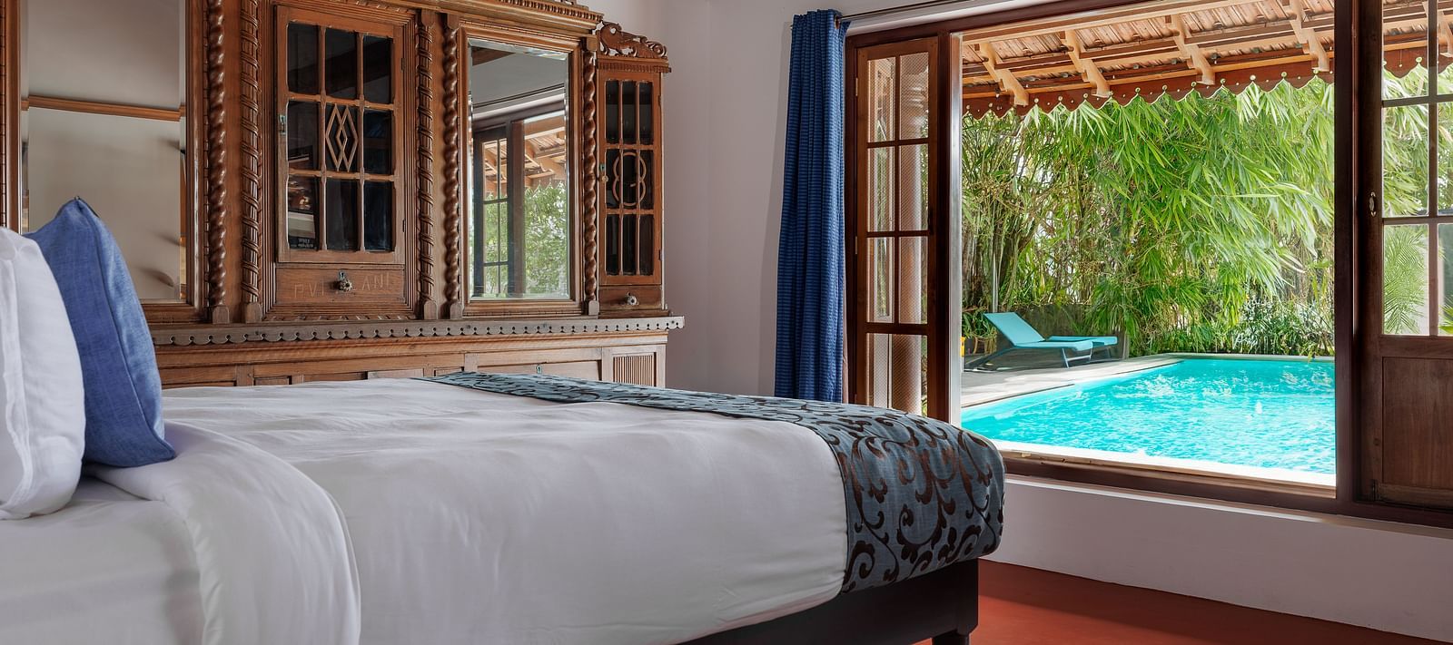 A shot of a room taken from an angle showcasing the bed facing a huge window with the view of the pool outside - BluSalzz Villas - Muhamma Resort, Alleppey