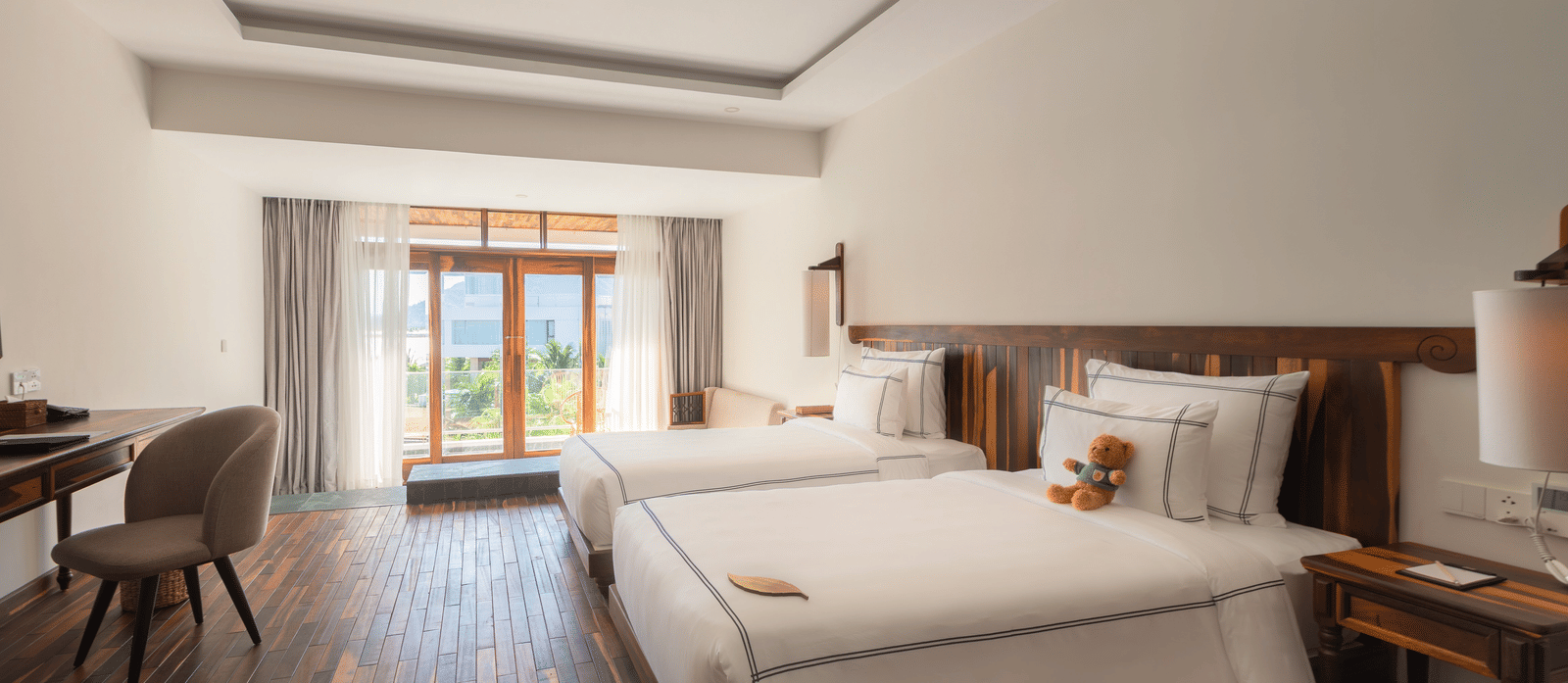 Balcony Room at Alibu Resort Nha Trang with twin bed, writing desk, lounge chair, and access to balcony.