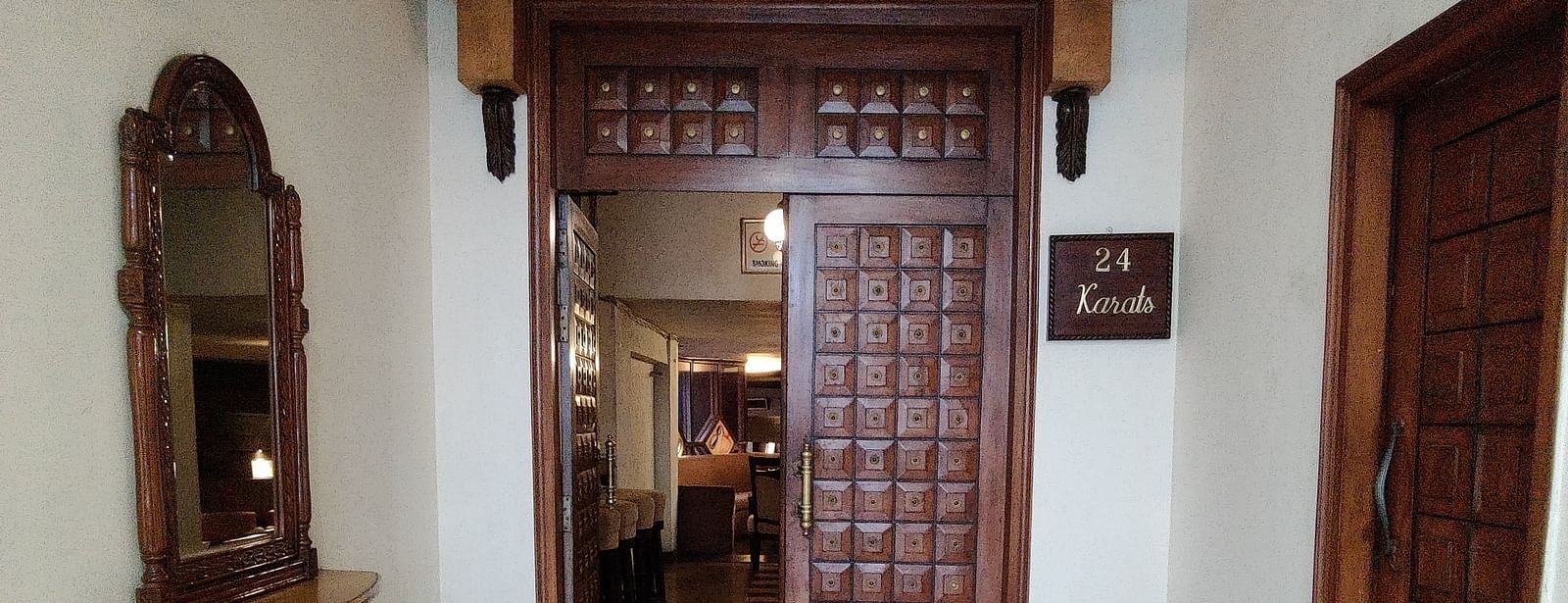 Entrance of the 24 Karats bar where two dark coloured doors are visible with an ornate pattern on the floor - Hotel Gold, Panipat