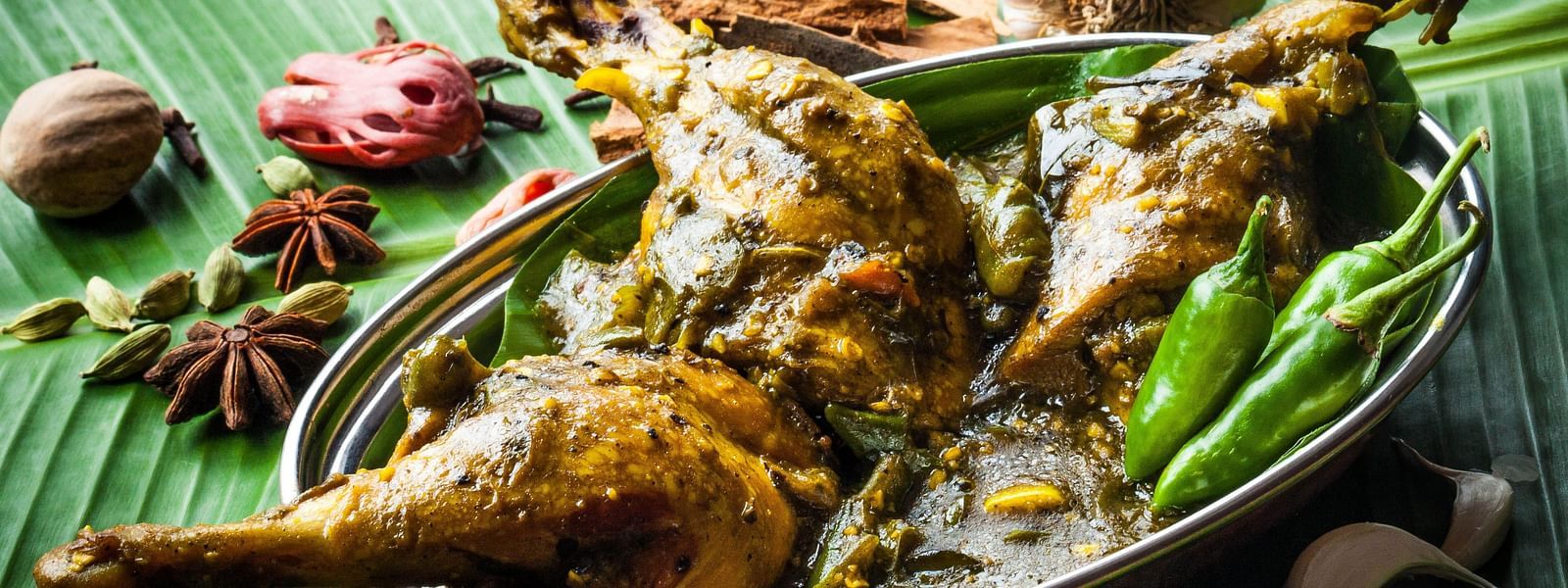 Aromatic and spicy traditional roasted chicken served on a banana leaf, garnished with herbs, epitomizing authentic Indian cuisine.