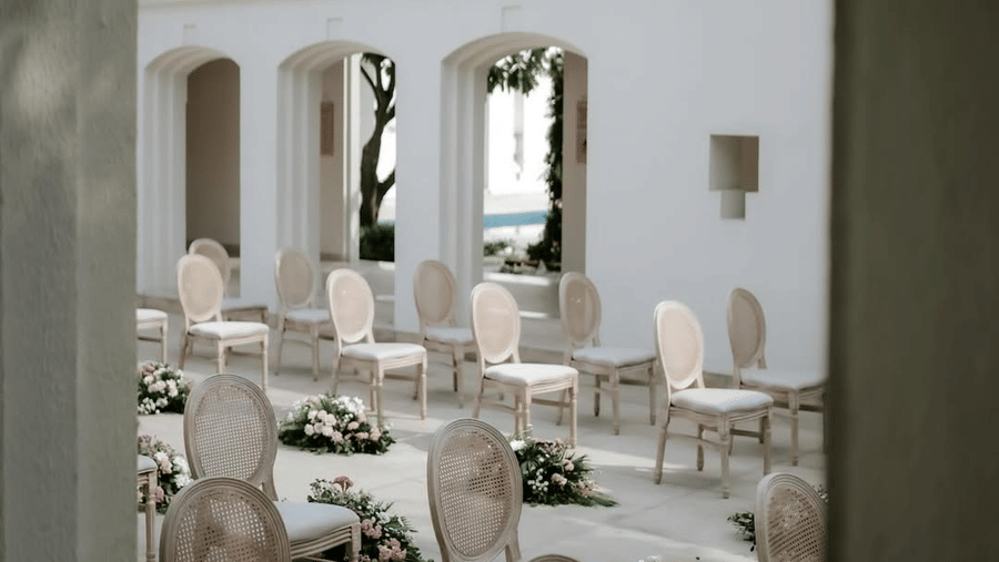 Courtyard seating at Marasa Sarovar Premiere, Bodhgaya with arranged chairs, floral aisle accents, arched corridors, tiled roof, and open-air setting