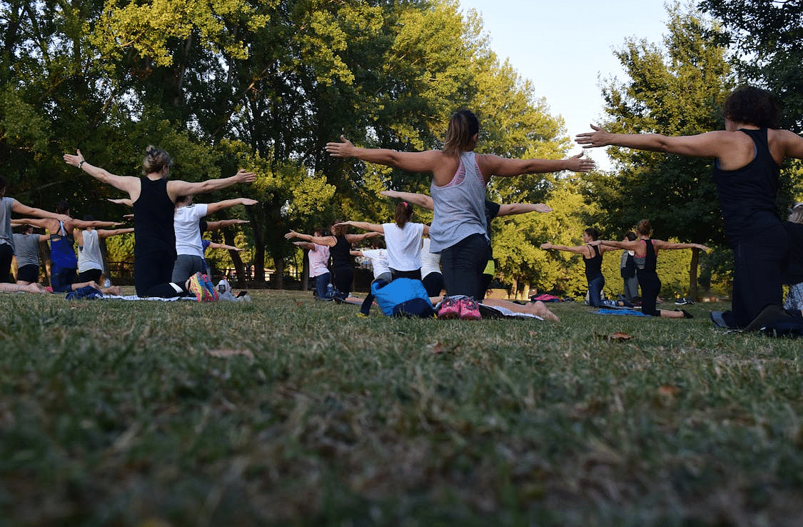 image of a group of people doing yoga in open air surrounded with lush greenery