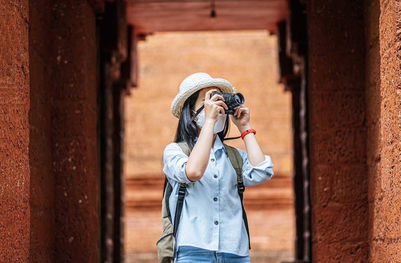 A person taking a photograph with a camera through an arched doorway.