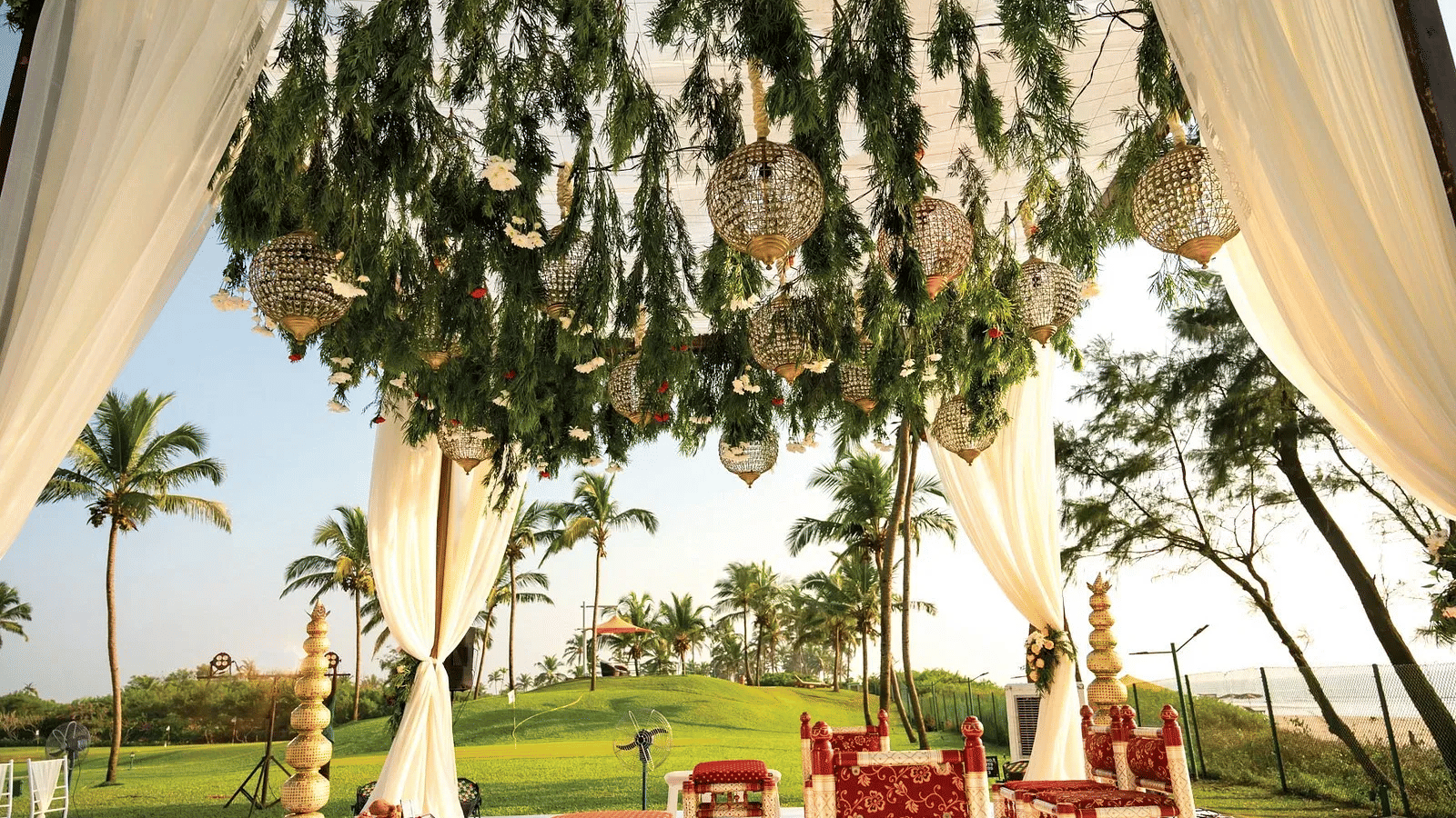 Elegant outdoor wedding ceremony setup with hanging basket lights and white draping at Caravela Beach Resort Goa
