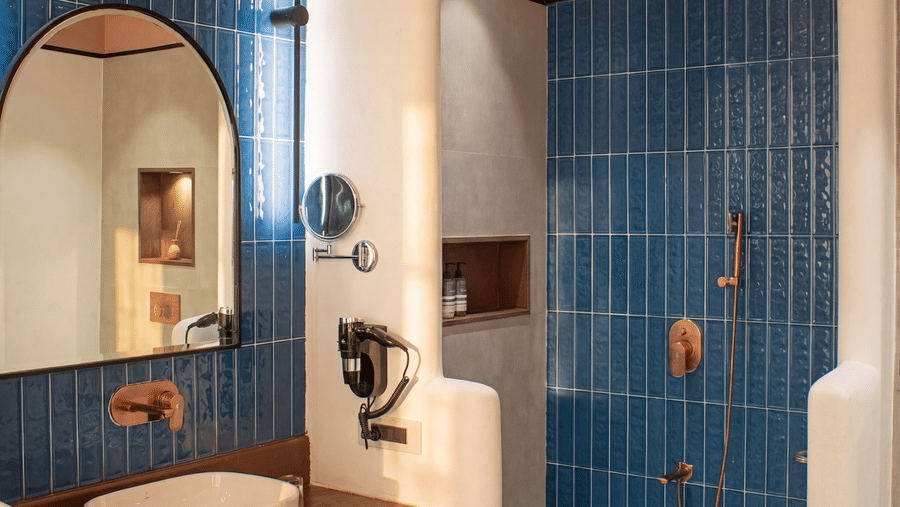 A modern bathroom vanity with an arched mirror, a white washbasin, and a wooden counter at The Sierra - By The Lake.