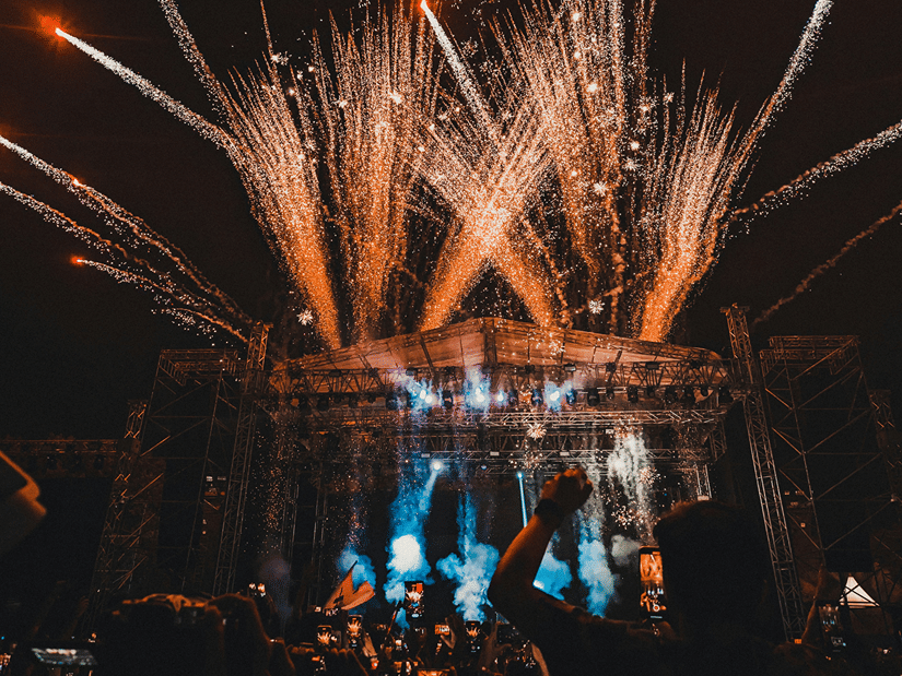 fireworks exploding behind the stage of a music festival