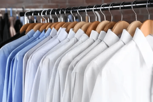 White and blue shirts on wooden hangers on a clothes rail