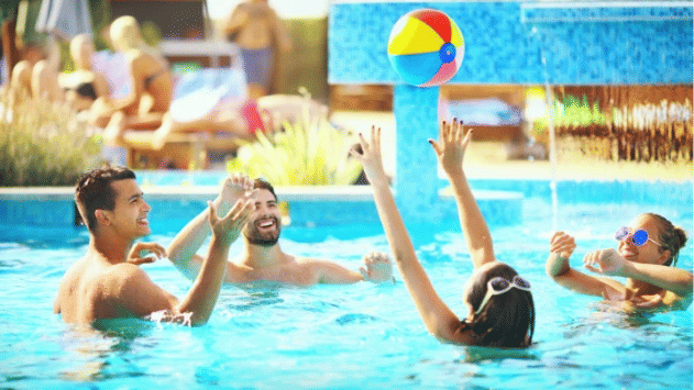 A group of people playing with a vibrant ball together in a pool, splashing water and laughing at S Hotel Montego Bay, Jamaica.
