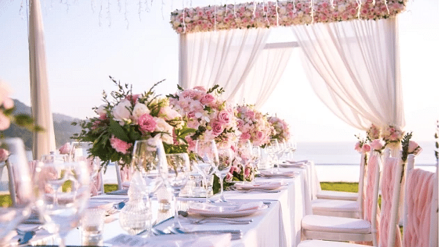 A wedding setup with a long table, an arch decorated with pink curtains near a beach - S Hotel Montego Bay, Jamaica