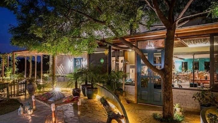 Outdoor dining area at Karma Chalets with seating under trees and warm lighting in the evening.