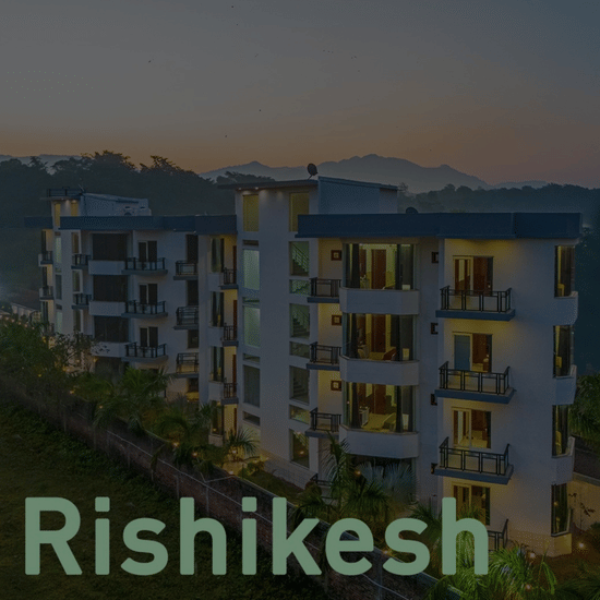 Nature Trails Rishikesh hotel card showing modern multi-storey building with balconies at dusk, set against hills in Rishikesh