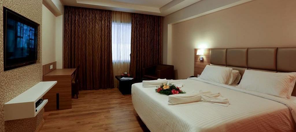 Spacious room with television, bed and table at Fressotel Seetharam, Coimbatore