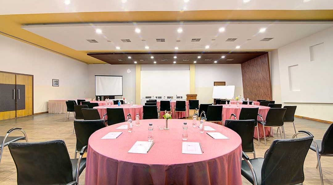 a banquet hall with cluster style seating and round tables - Camel Valley Resort, Igatpuri