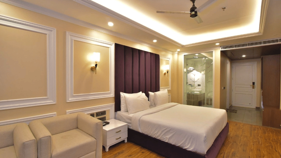 Luxury Rooms with balcony in Dalhousie with double bed, golden lighting, and attached seating space at Claret Inn, Dalhousie.