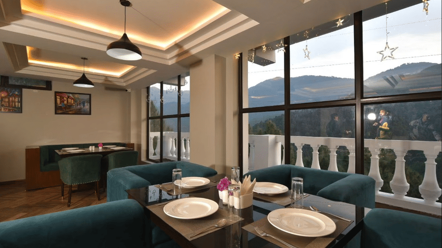 Chic dining area with teal chairs, glass windows, and elegant table settings at Claret Inn, Dalhousie.