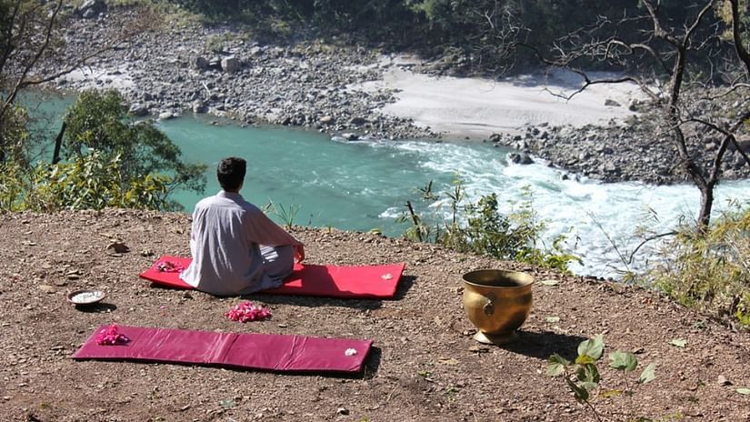 Man meditating near a flowing river