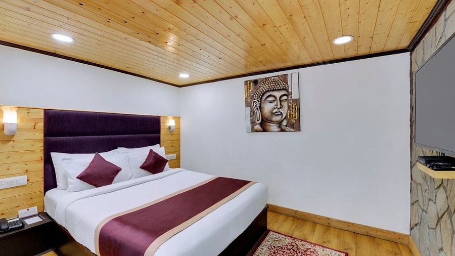 Premium Double bedroom with a large bed with a purple headrest and side lamps - Sumitel Boutique Resort, Darjeeling