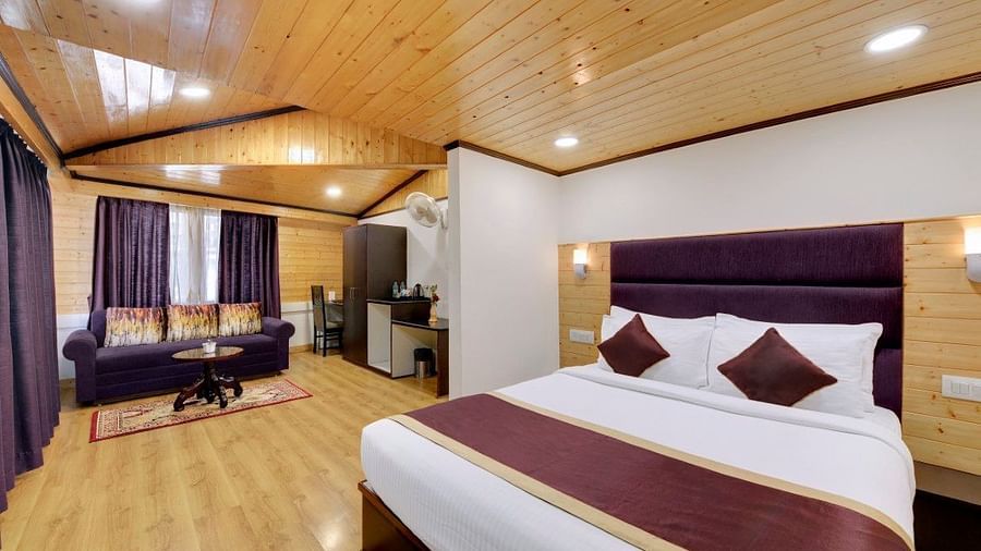 A bedroom with purple curtains and sofas and chairs for seating with a table - Sumitel Boutique Resort, Darjeeling