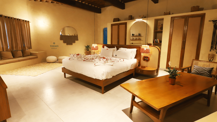 The Classic king villas with a plush bed and wooden furnishing at interior of Classic Villas arrayed with a sofa, trinkets and a lamp hanging from the ceiling at Themis Mudhouse - A Nature's Retreat Resort & Wellness