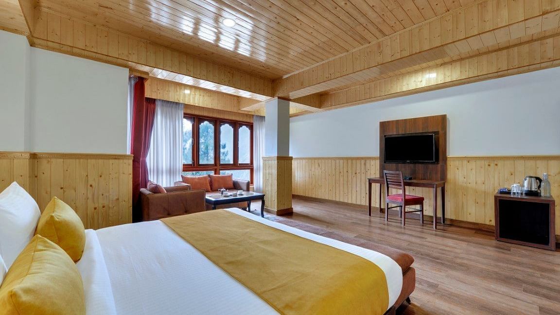 Picture of a room at or hotel that has wooden furnishing, king size bed, a flat screen television and seating area by the window  | Yashshree Lachung