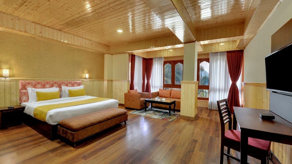 Shot of a room in our hotel with a king size bed, wooden flooring, a flat screen television and windows that overlook the mountains  | Yashshree Lachung
