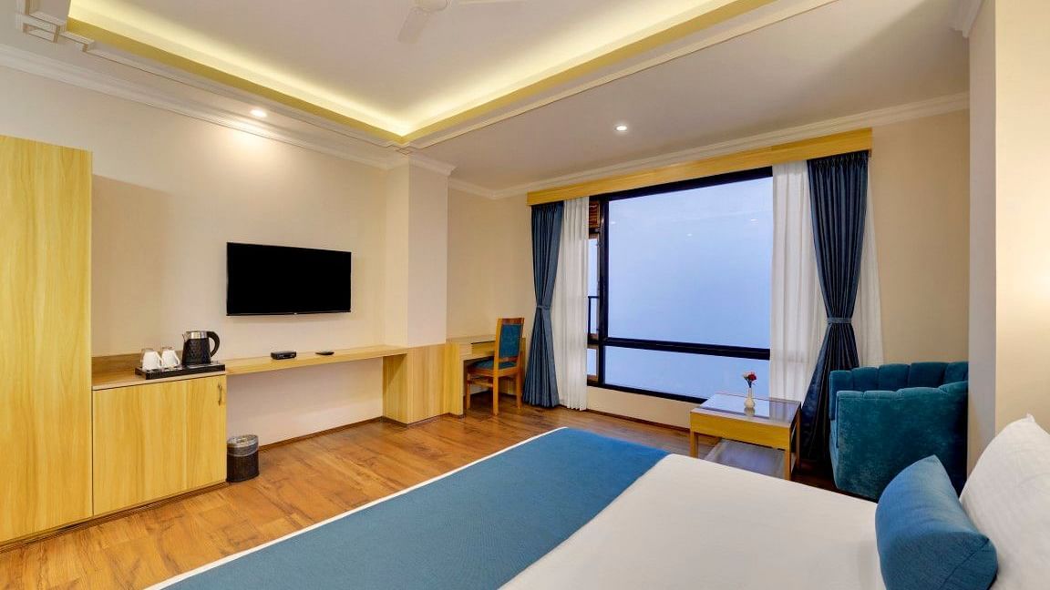 An image of a premium room with bed, flat screen TV, work desk, chair and window over looking the mountains - Yashshree Sikkim Blossom, Gangtok