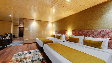 Image of two king size bed in a expansive room with a yellow blanket and wooden furnishing | Yashshree Lachung