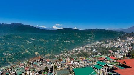 An image of a town with the backdrop of mountains and blue sky which is also the view from Yashshree Sikkim Blossom, Gangtok