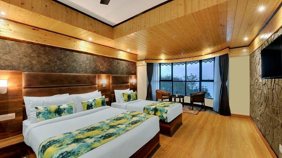 An image of Sumitel Queensyard premium room with king size bed and a single bed, tv, ceiling fan, and a chair and a table