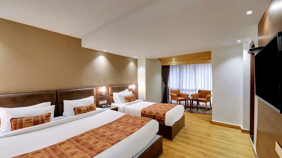 An image of a room with a queen size bed and a single bed with TV and minimal decoration - Sumitel Vista TV Tower