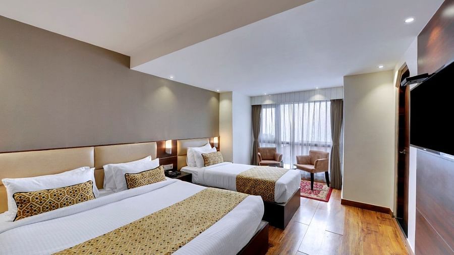 An image of a room with a queen size bed and a single bed with TV and minimal decoration - Sumitel Vista TV Tower