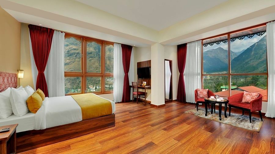 Shot of the luxurious suite at our hotel with a king size bed, wooden flooring, a cosy  seating area  | Yashshree Lachung