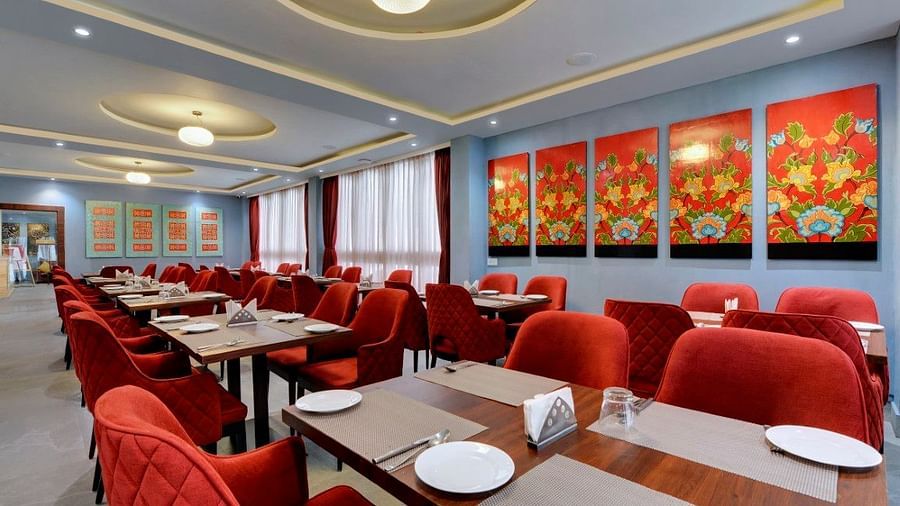 Shot of the restaurant at our hotel featuring  red chairs and table with plates kept on the table  | Yashshree Lachung
