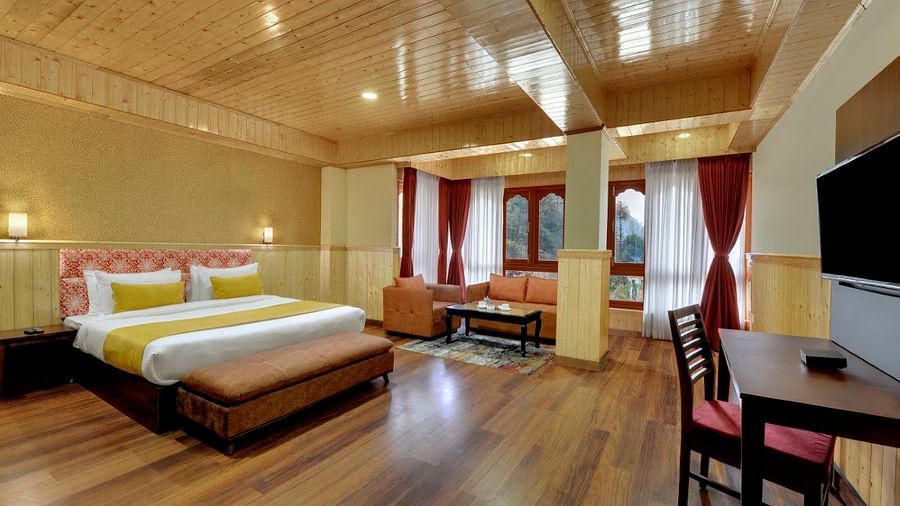 Shot of a room in our hotel with a king size bed, wooden flooring, a flat screen television and windows that overlook the mountains  | Yashshree Lachung
