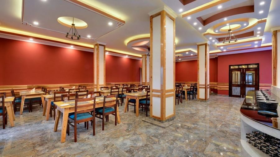 Spacious and well-lit dining area of Blue Charcoal Restaurant at Yashshree Sikkim Blossom in Gangtok with elegant decor and neatly arranged tables. 
