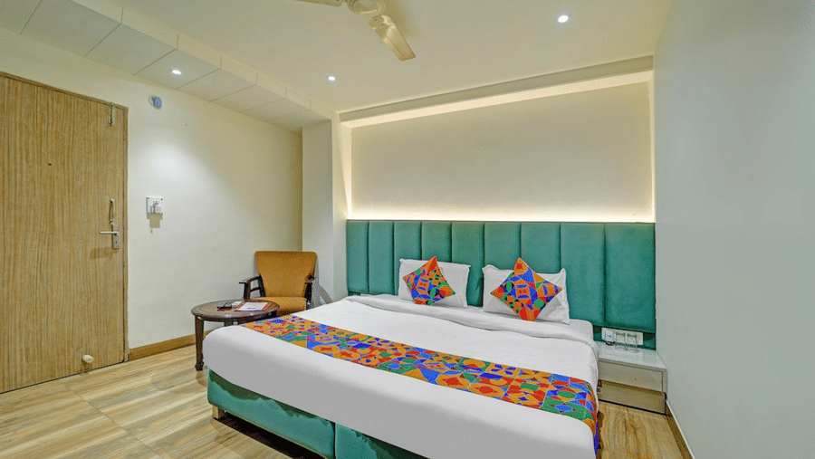 Contemporary deluxe room with twin beds, teal accent wall and warm lighting at Hotel Maurya, Bhopal.
