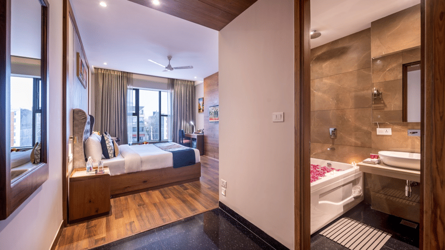 View from a hotel Club Room hallway, looking into the bedroom and bathroom, with wooden flooring and mirrors on the wall.