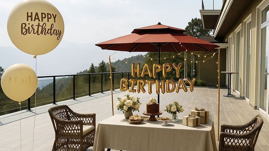  Daytime birthday celebration on the terrace at The Manor Sports & Wellness Hotel, featuring a decorated table, large balloons, wrapped gifts, and mountain views.