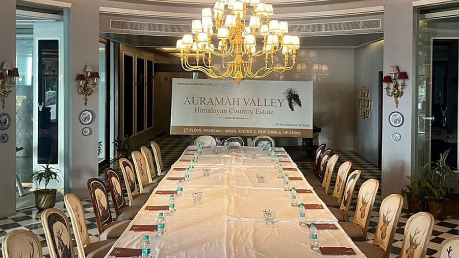  Formal meeting setup with long table and plush chairs under a chandelier at The Manor Sports & Wellness Hotel, perfect for conferences and corporate gatherings.